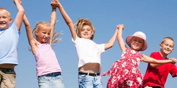 Group happy children jumping on summer meadow against blue sky